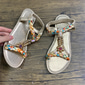 Flache Damensandalen in Goldmetallic mit geflochtenem Riemen mit Blumenmuster und Schmucksteinverzierung – lässiges Sommerschuhwerk für Strand, Pool und Urlaub